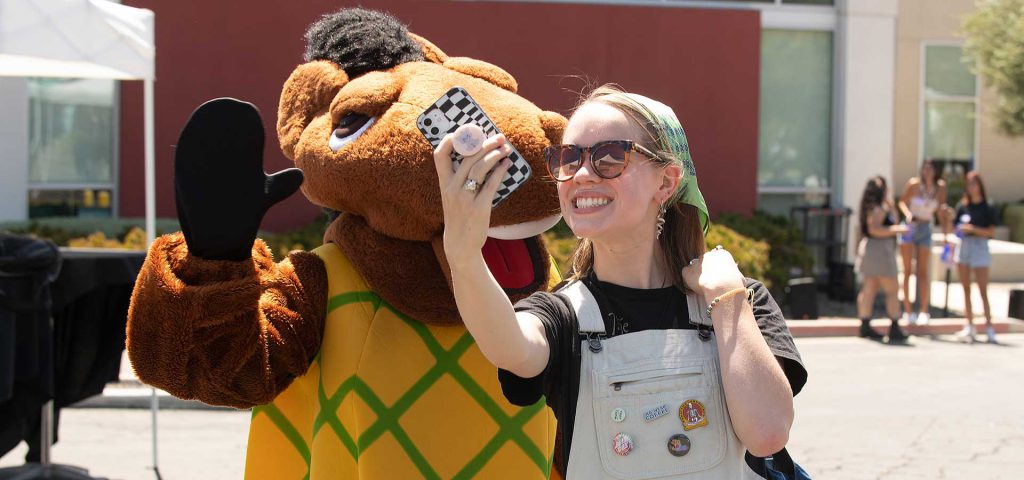 A female student takes a selfie with Pineapple Billy Bronco.