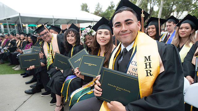 A group of students smile during the College of business administration commencement ceremony.