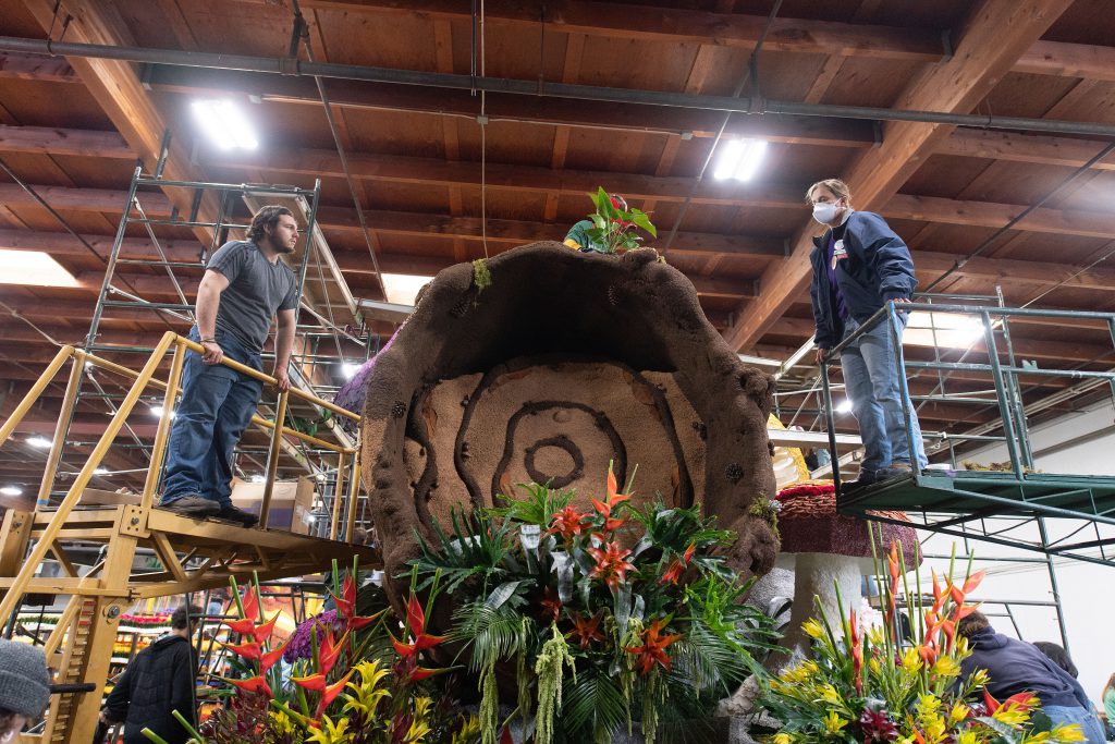 Two students on scaffolding look over the Rose Parade Float.
