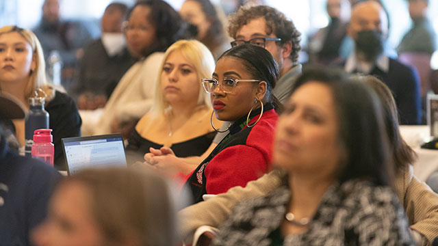 A group of people sitting at a table listening to a discussion.