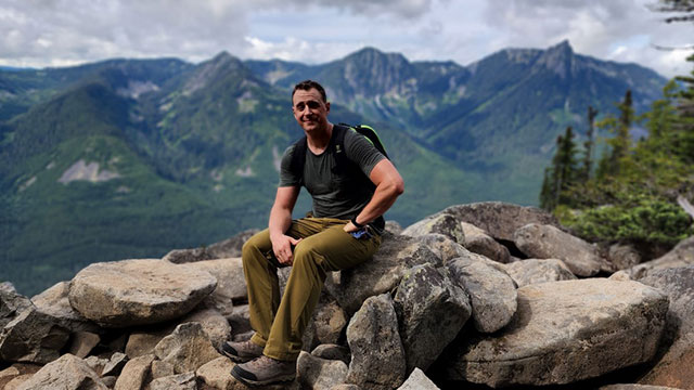 Jason Jones siting on a mountain top.