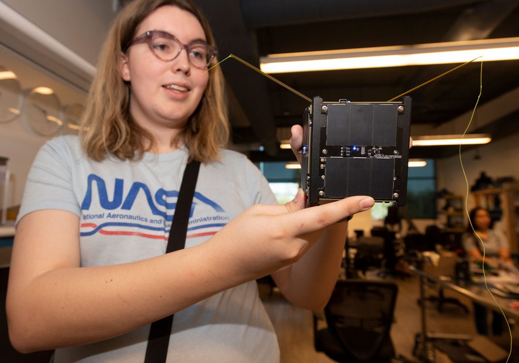 Female student holds a CubeSat.