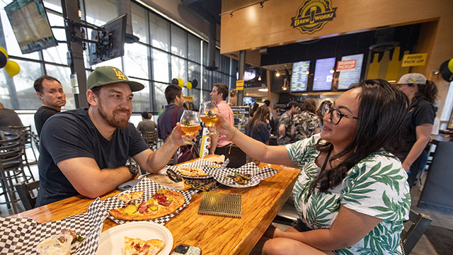 Two people cheers with glasses during the Brew Works Anniversary.