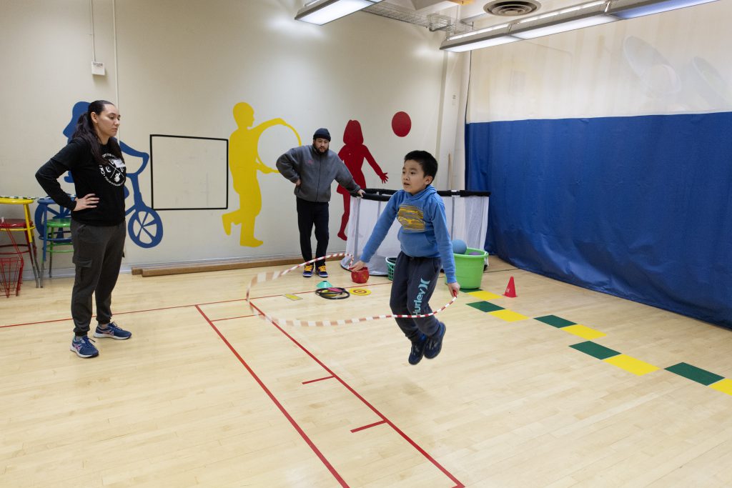 A therapist oversees a child doing jump rope. 