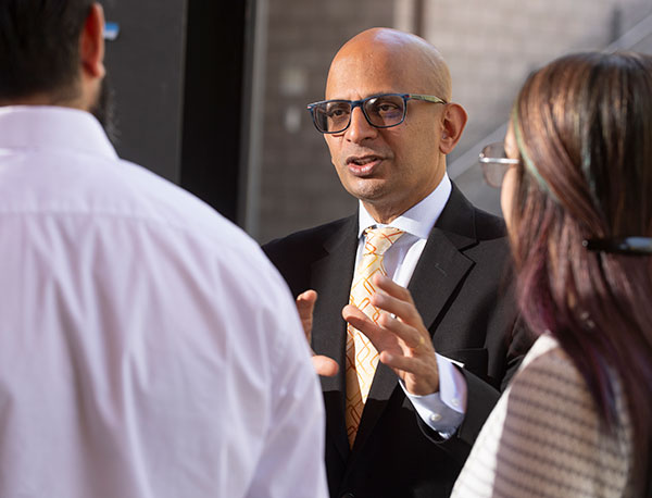 Dean Krishnamurthy speaking to colleagues.