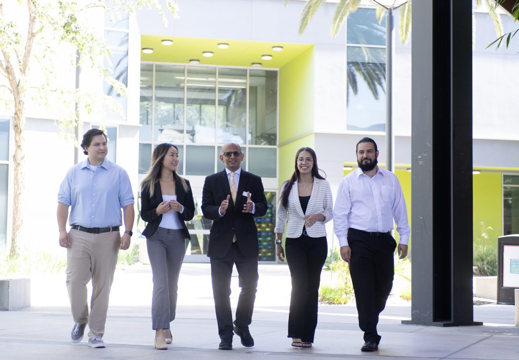 Dean Sandeep Krishnamurthy walks with students at the College of Business Administration..