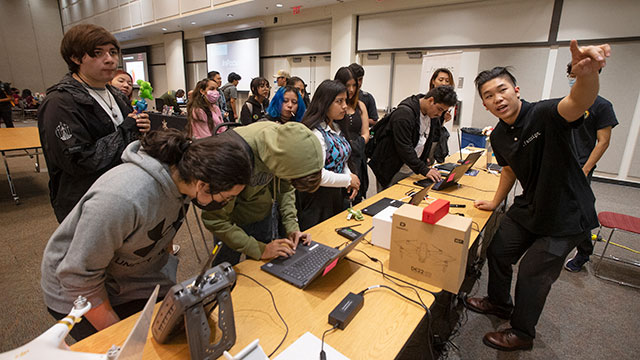 A group of students at a table looking at a presentation during the 2022 Cyber Security Fair.