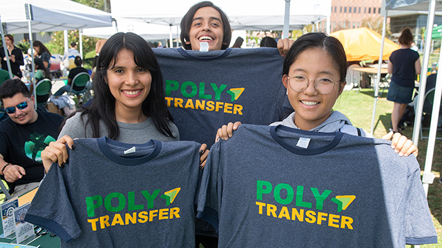 Students smile while holding a Poly Tranfer t-shirt.