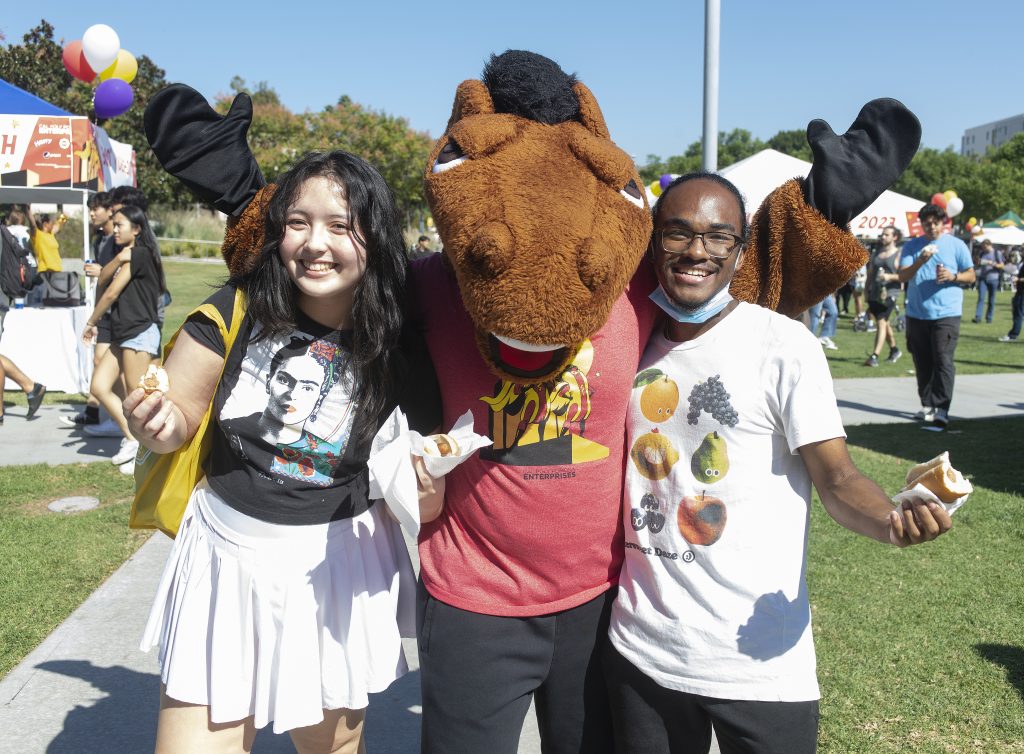 Two students pose with Billy Bronco at the 2023 Hot Dog Caper.