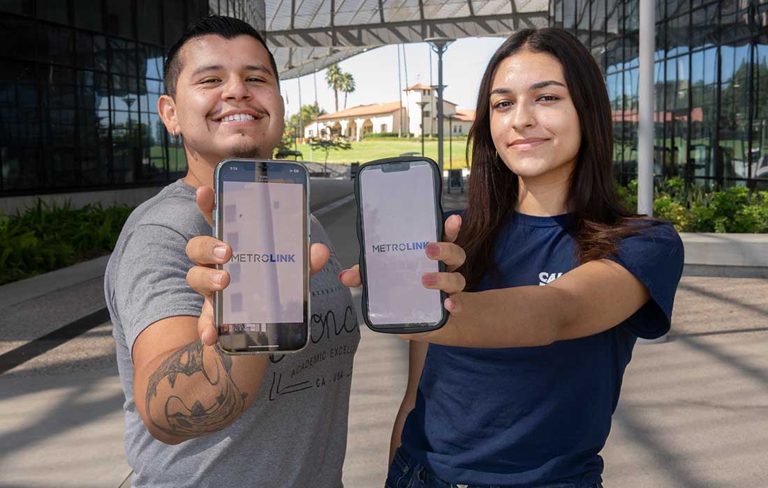 Two students hold their cell phones showing the Meltrolink app.