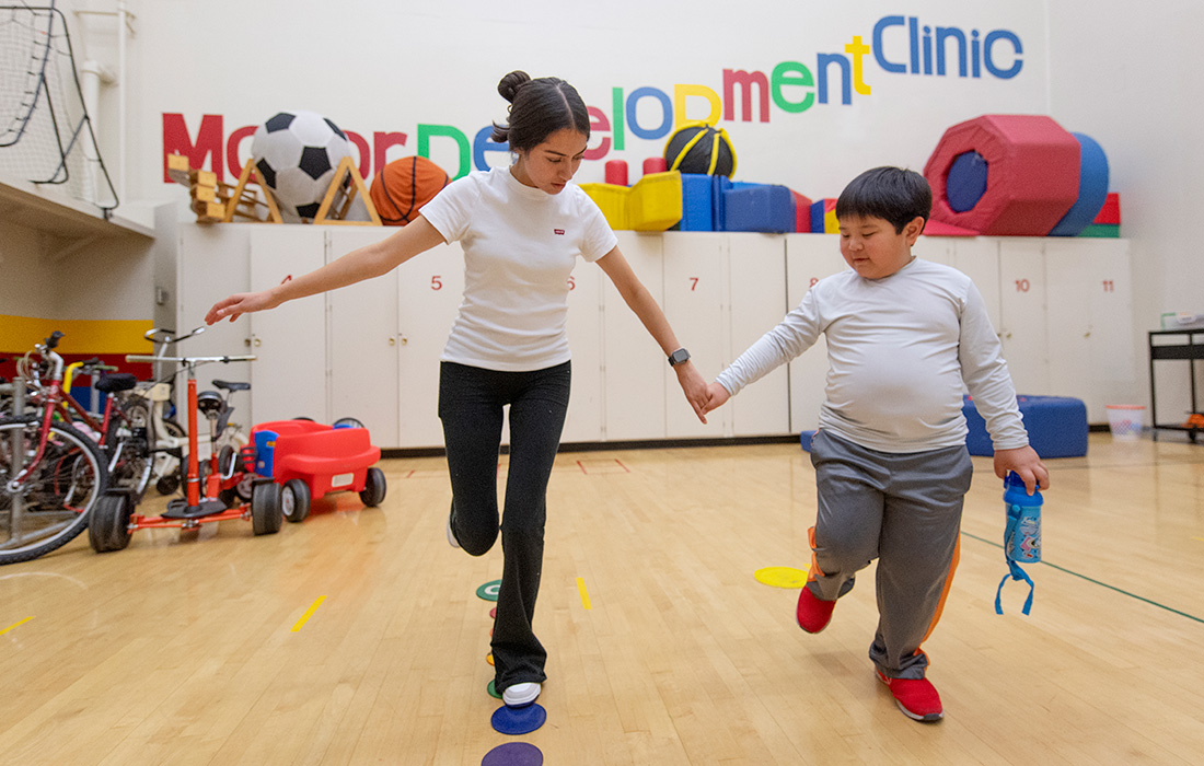 Motor Development Clinic student works with a child on his balance.