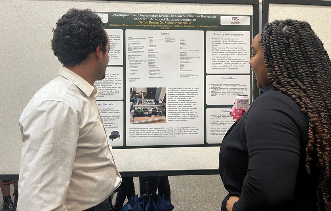 A male and female look over a poster board during a student research conference