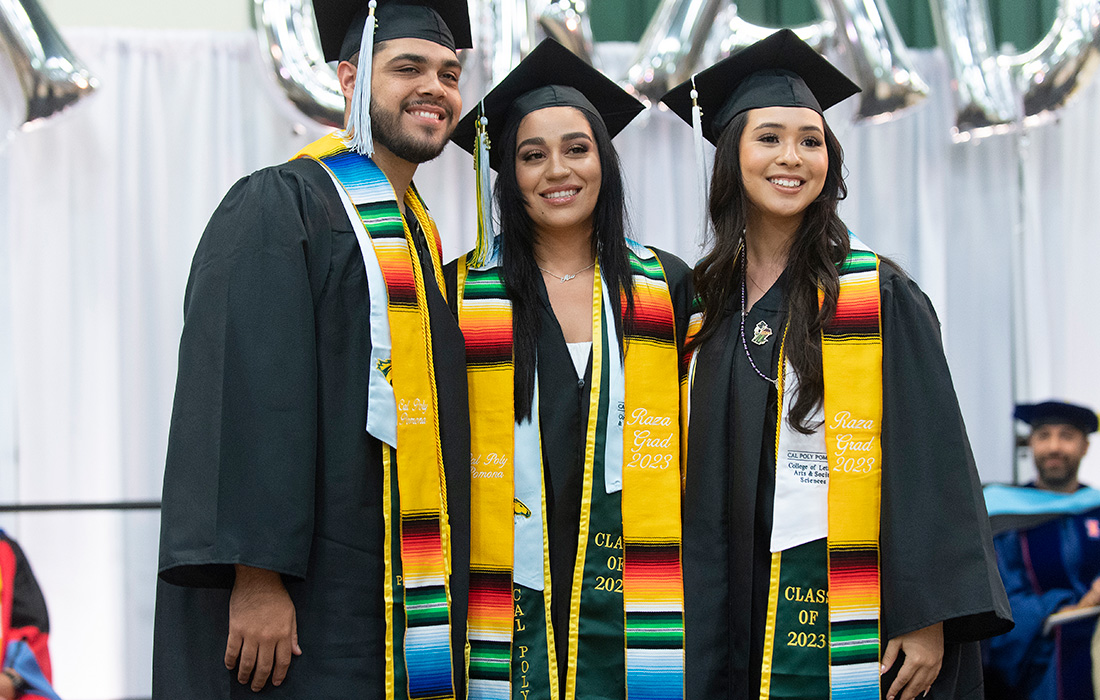 Three students smile during the 2023 Raza Graduation ceremony.