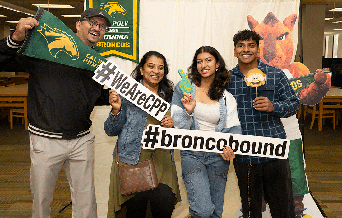 a family at Bronco Bound take a picture with a Billy Bronco cutout.
