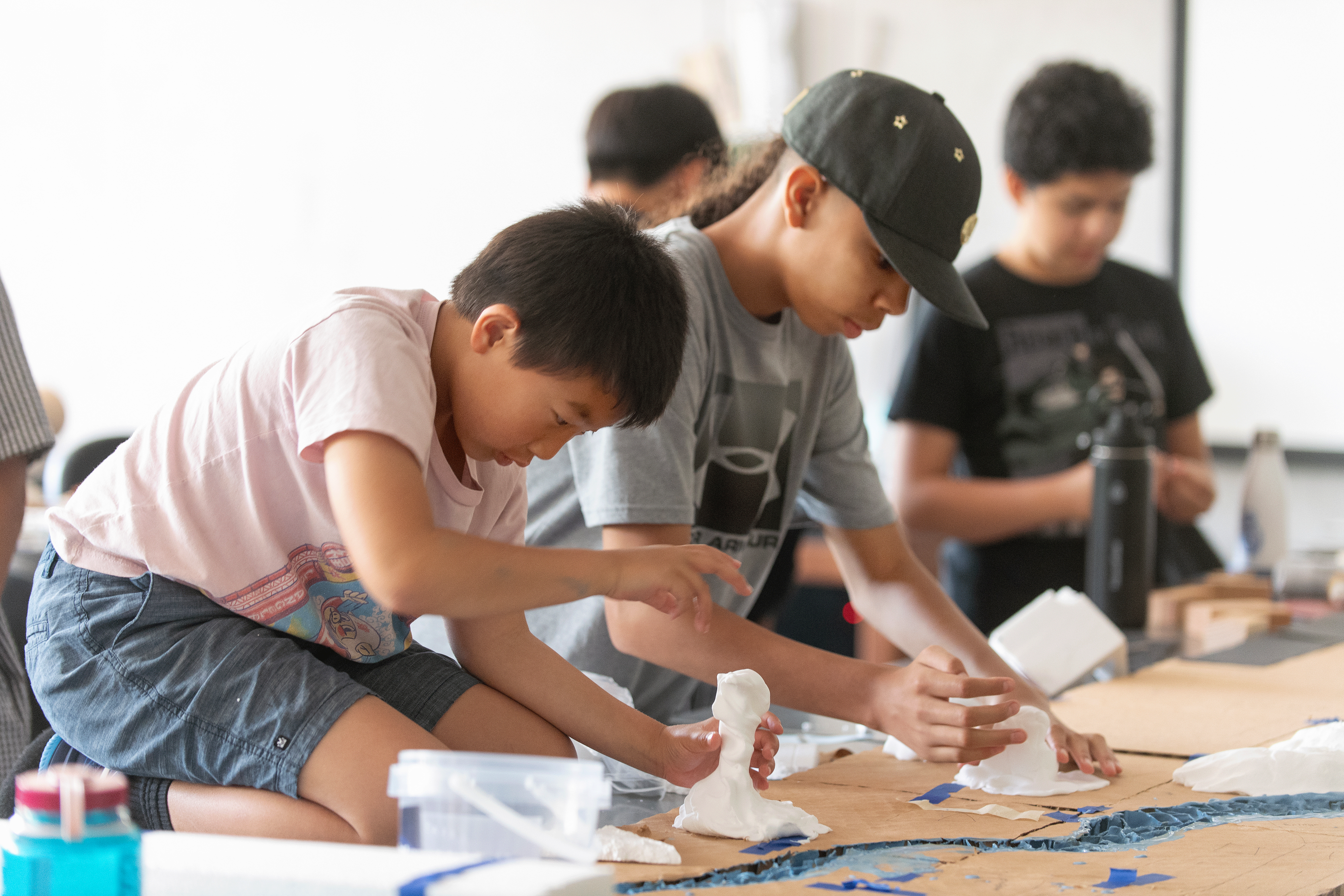 Two students make mountains out of clay