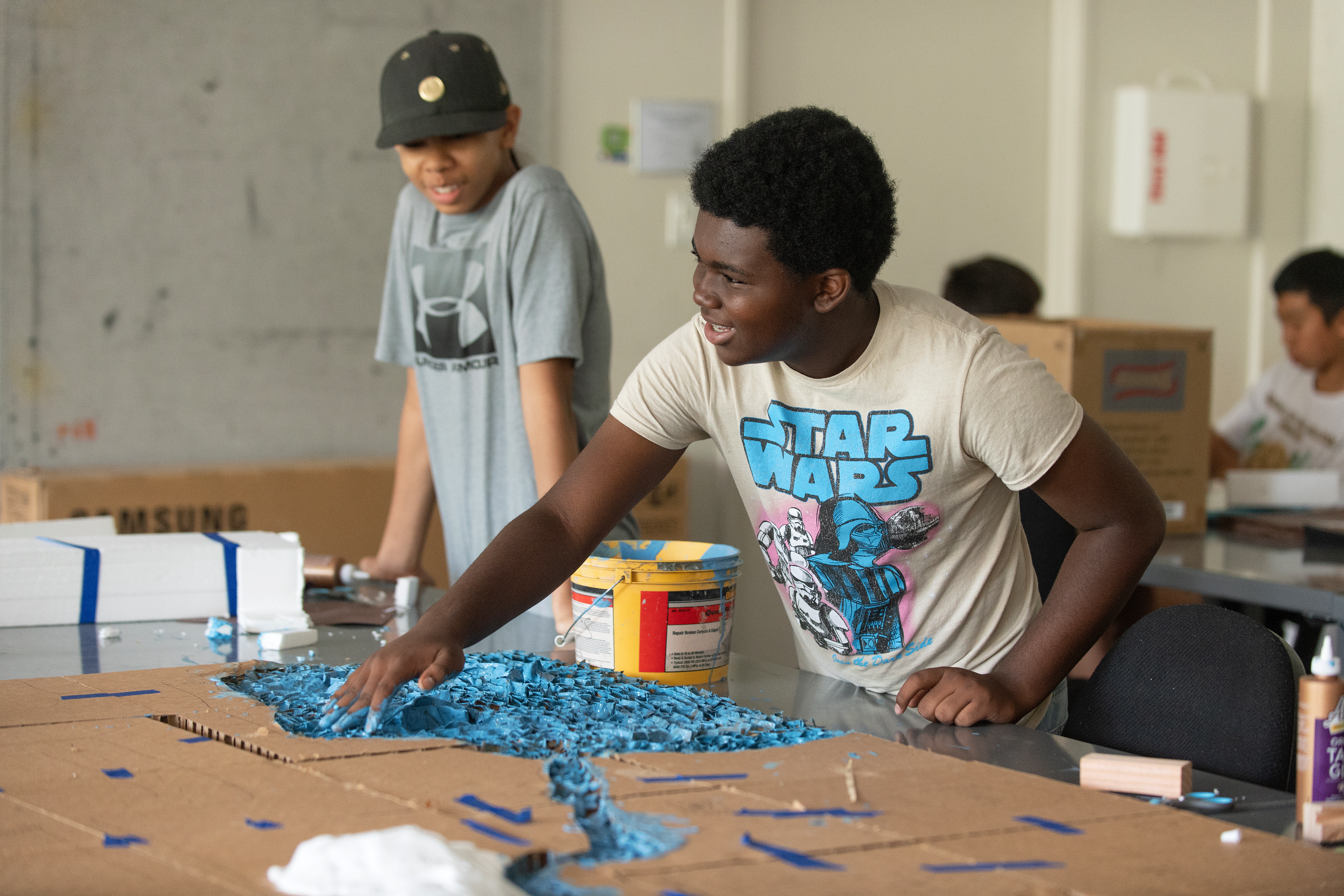T.J. Kavia spreads paint into what will become a river running through a city