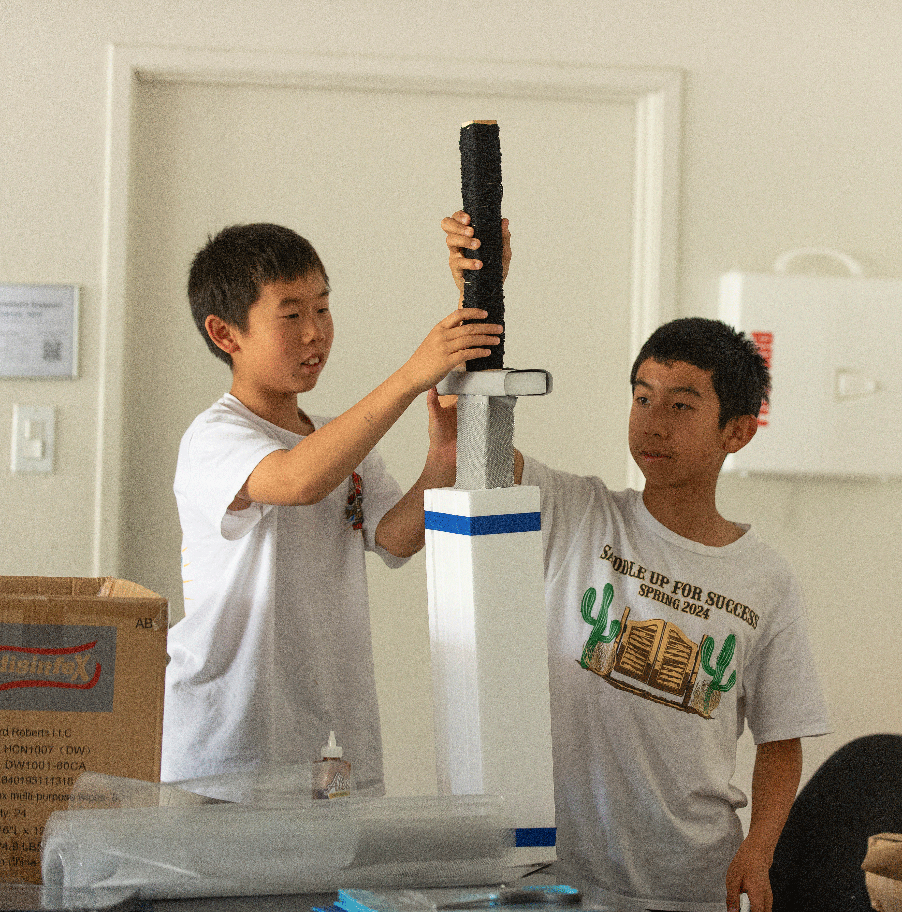 Two boys work on a tower