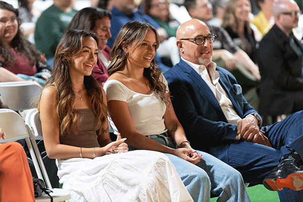 Terri Gomez' husband and two daughters smile while she speaks during the Academic Affairs Forum.