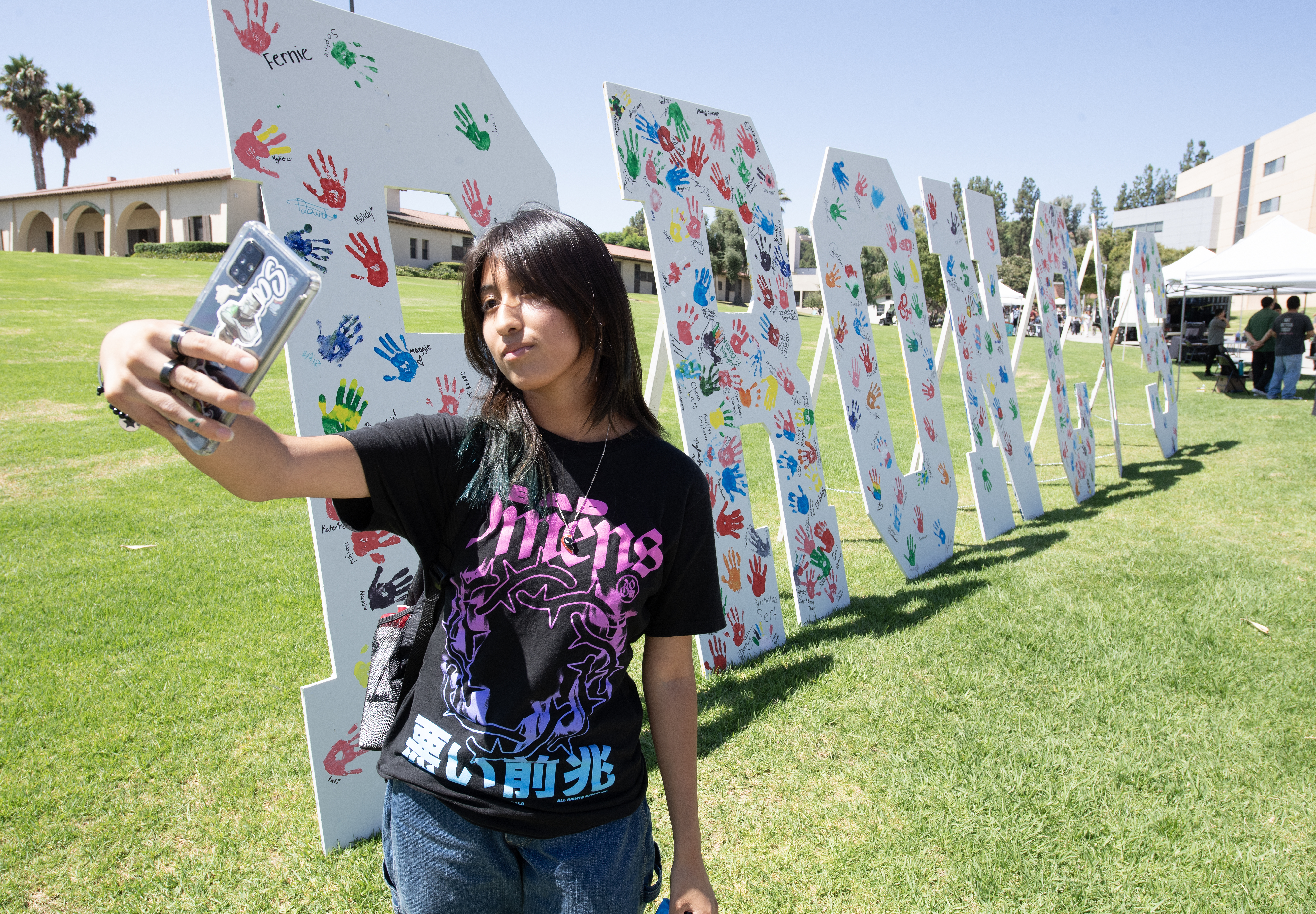 Female student takes a selfie with the CPP Bronco Letters.