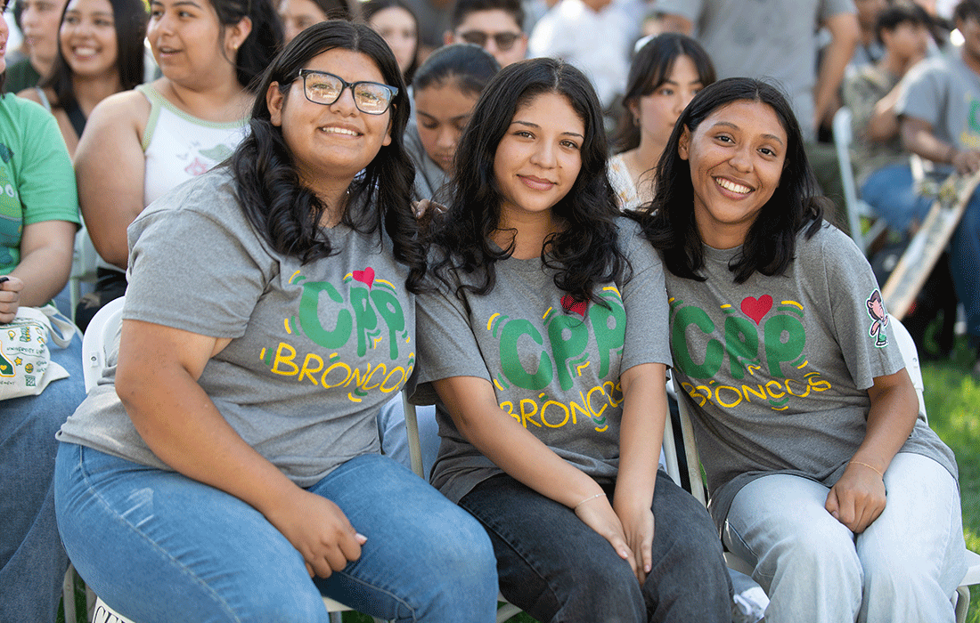 Three female students smile during the New Student Convocation at CPP.