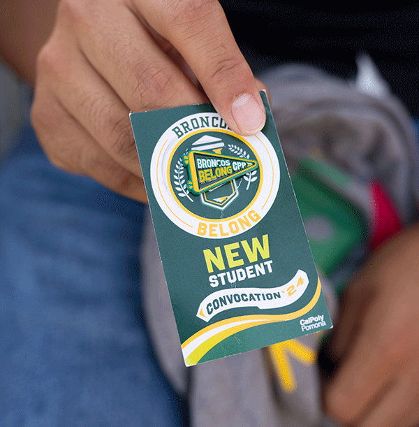 A student holds a Broncos Belong pin.