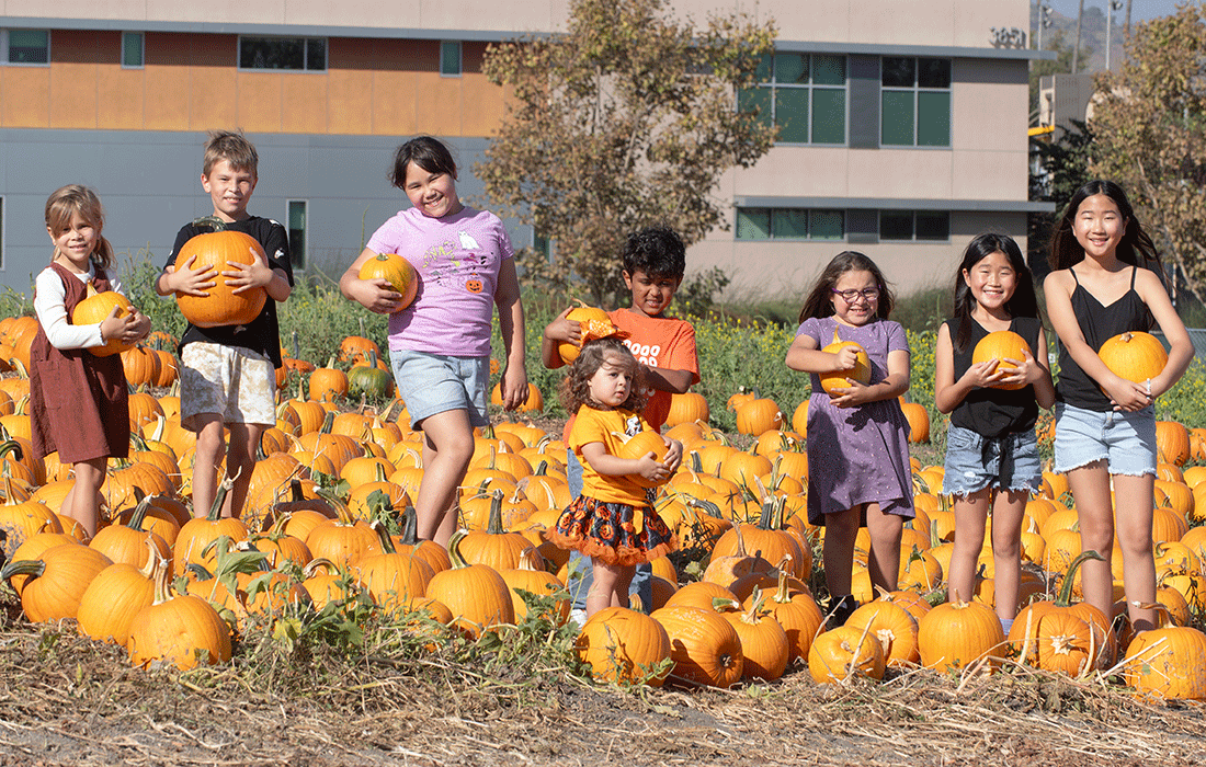 A group of kids pose with pumpkins at the Cal Poly Pomona pumpkin patch.