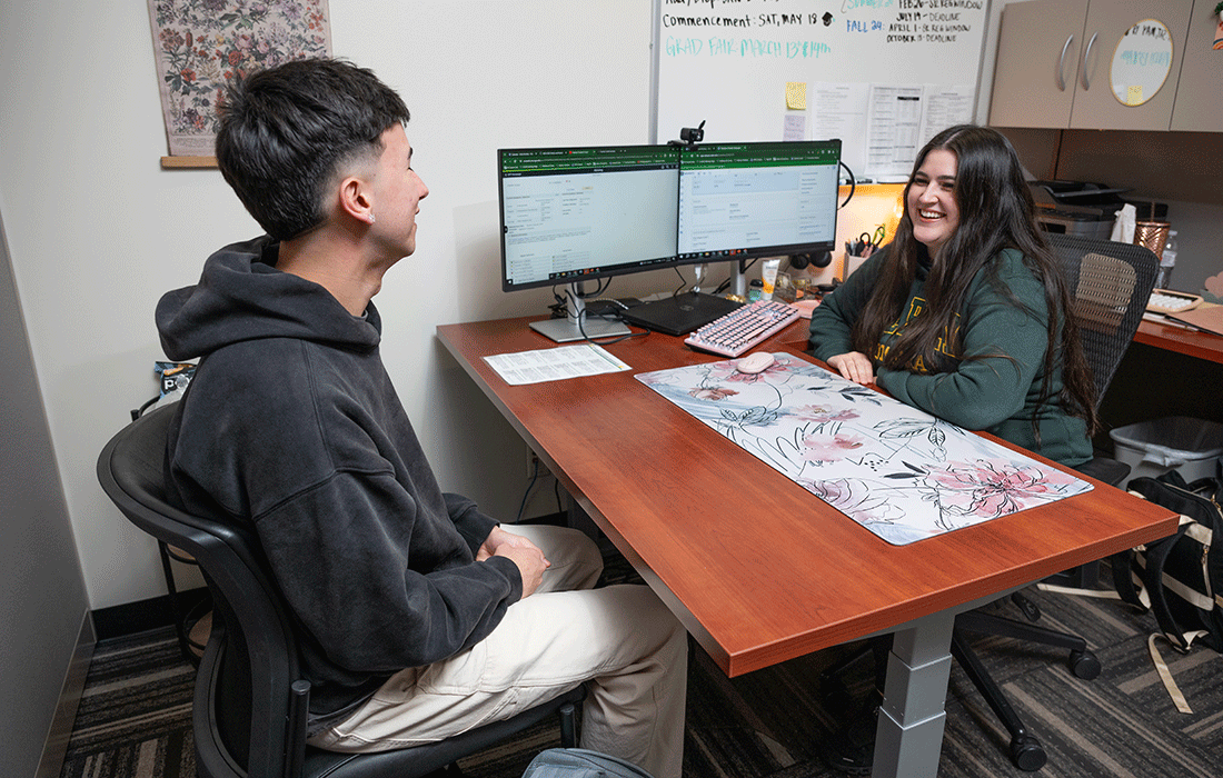Female advisor meets with male student in office.