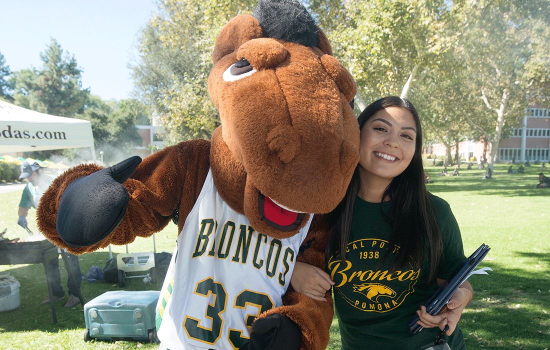 Female student hugs Billy Bronco as he gives a thumbs up.