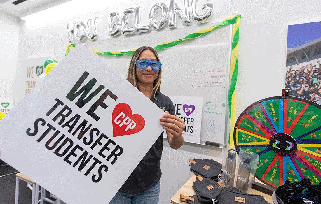 A female student holds a sign that says We Love Transfer Students.
