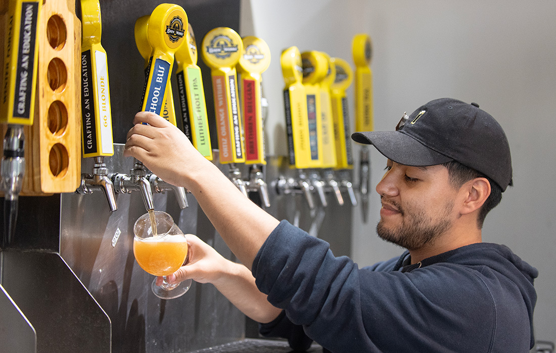 Employee at BrewWorks pours beer into a glass.