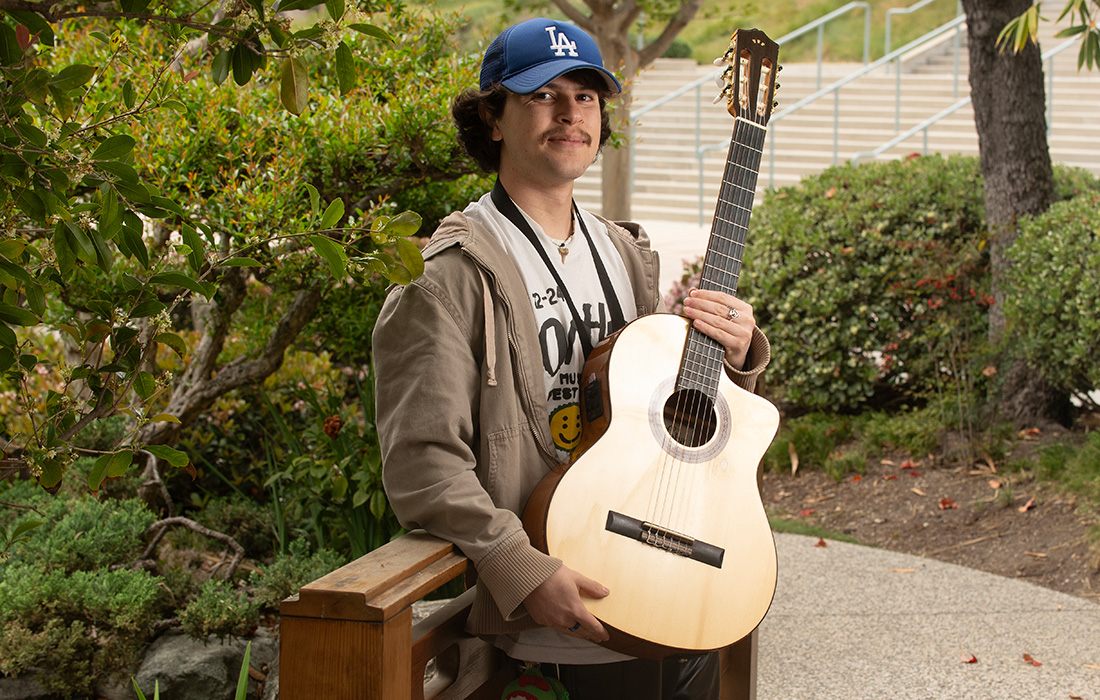 Juan Nunez holds a guitar at the Japanese Garden on campus.