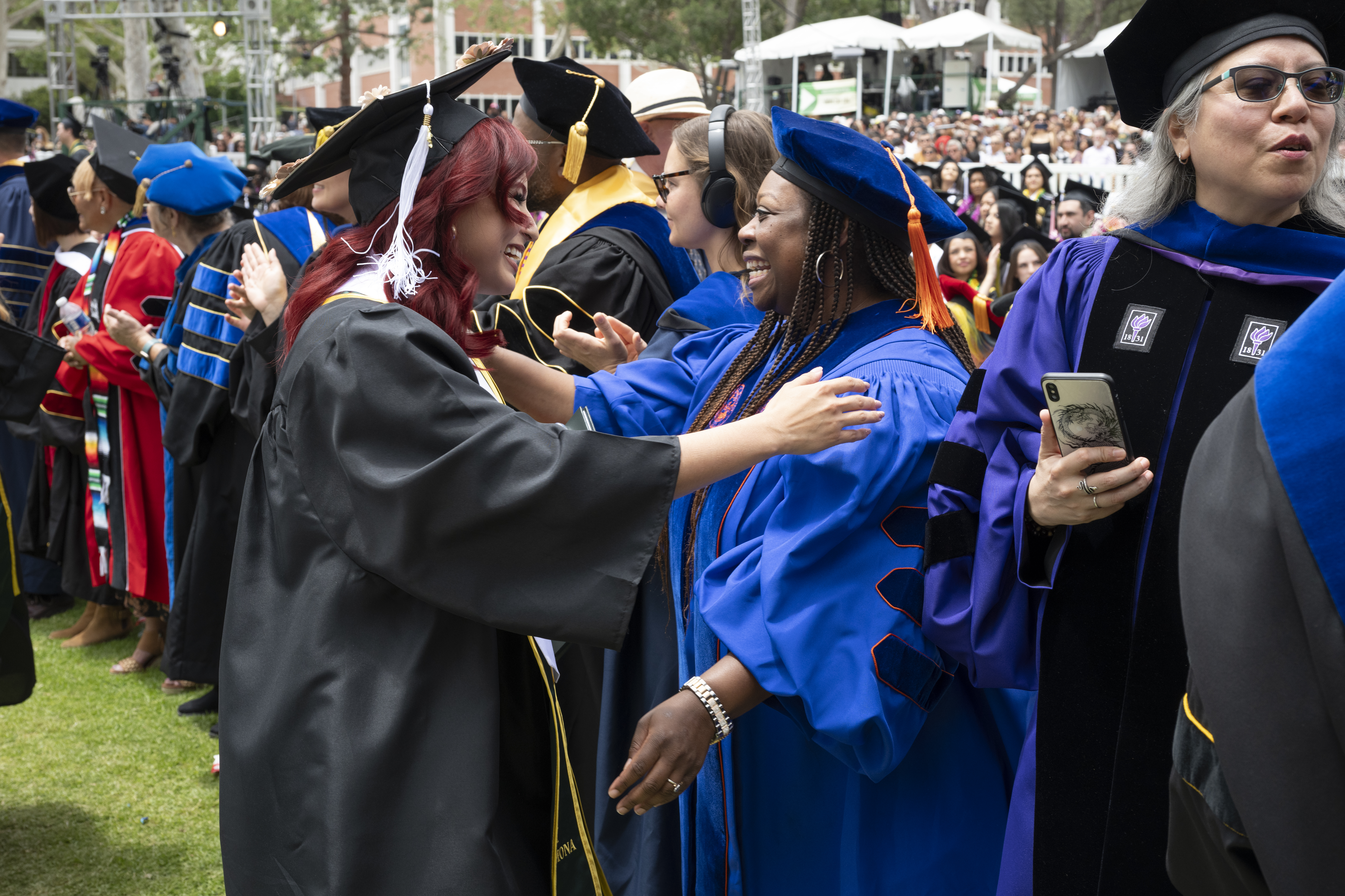 A faculty member shakes the hand of a new graduate during commencement.