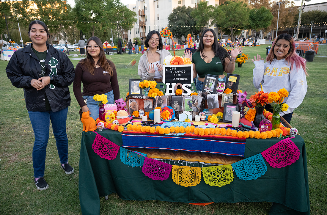 Students pose with an ofrenda on campus during the 2024 Dia De Los Muertos celebration 