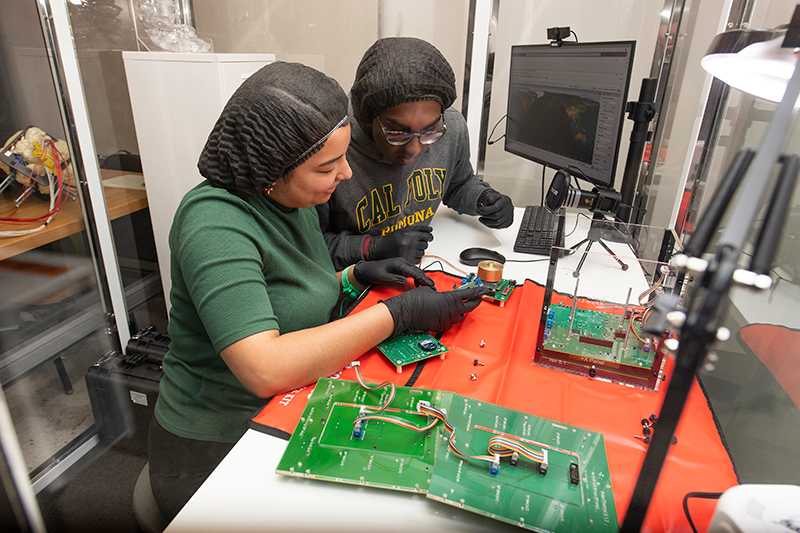 two female engineering students work on a computer board. 