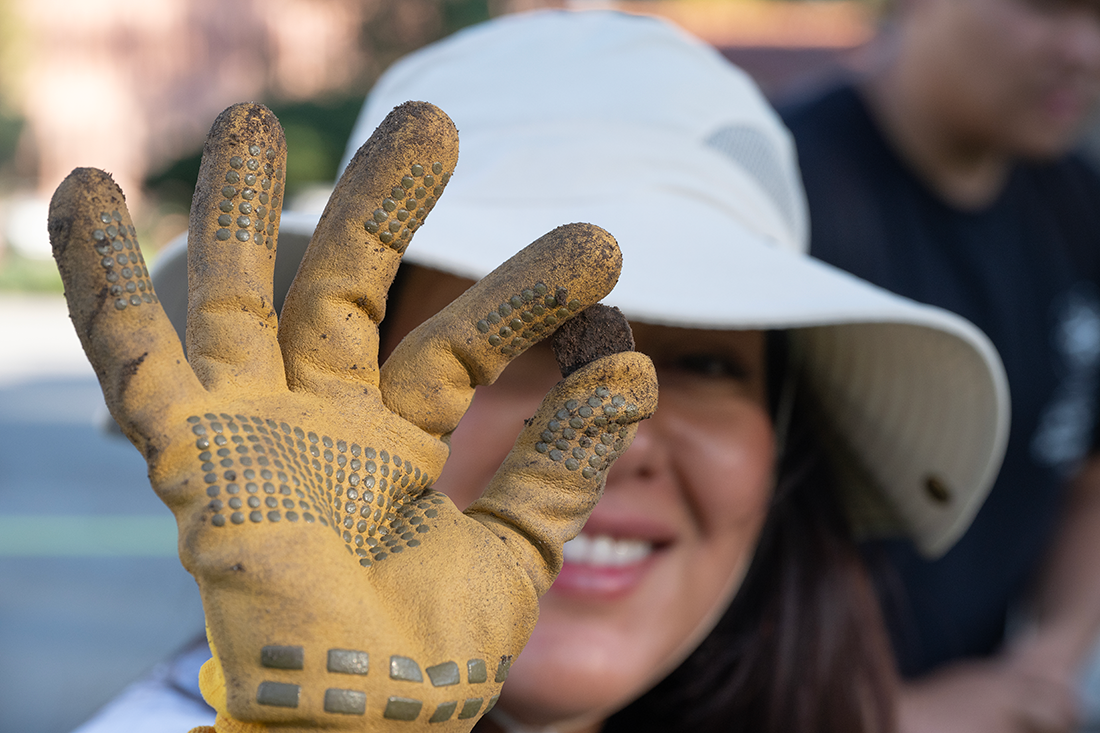 Female student holds something she found in the Quad.