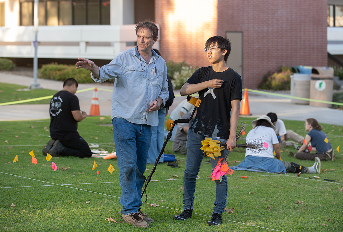 Professor and male student stand in the quad