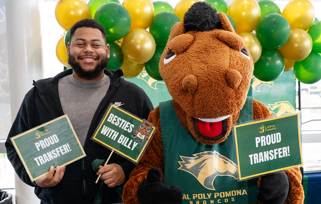Male Chaffey student Admit holds a sign standing next to Billy Bronco.