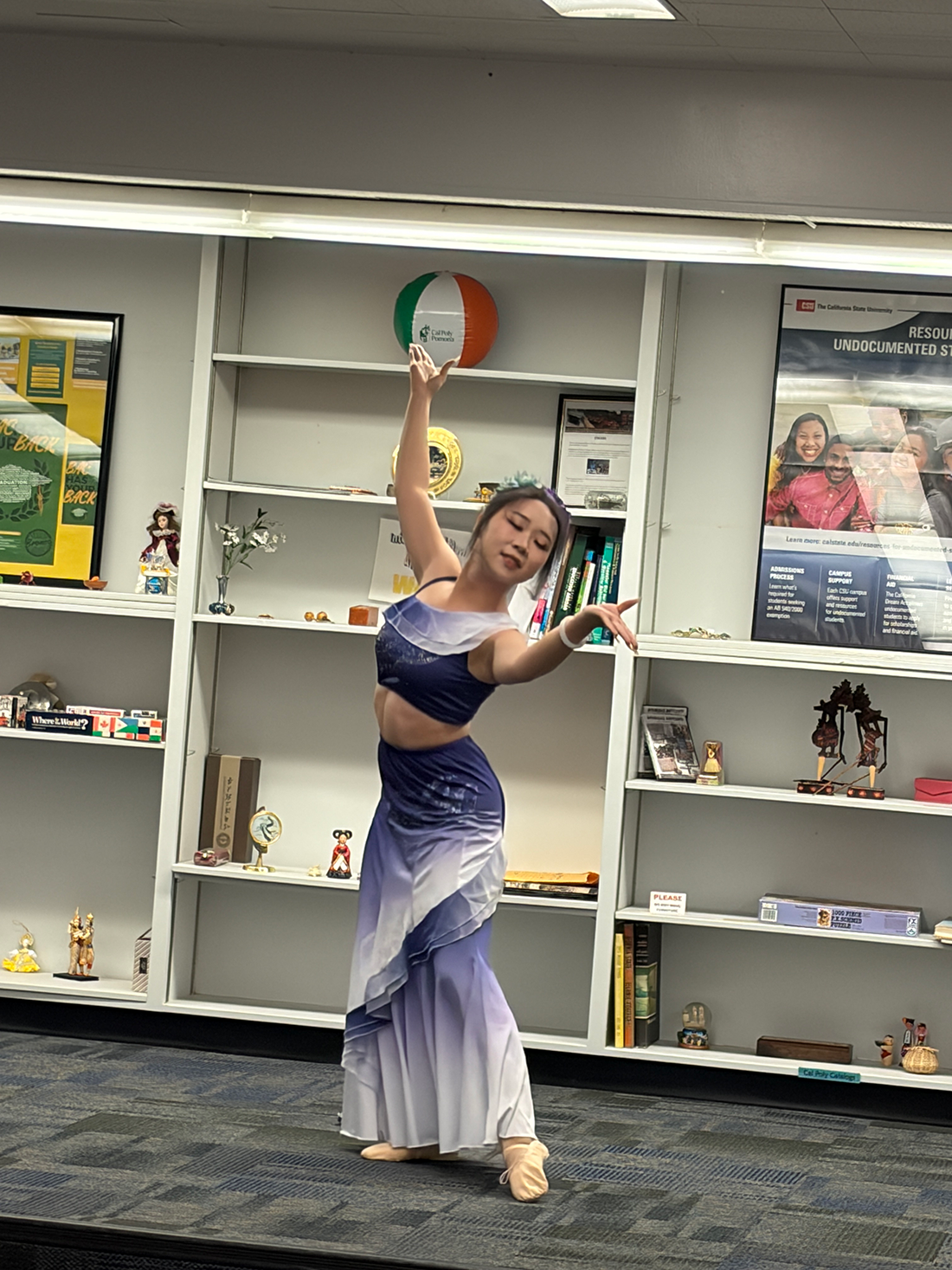 Female dancer during a dance move wearing a purple two piece costume.