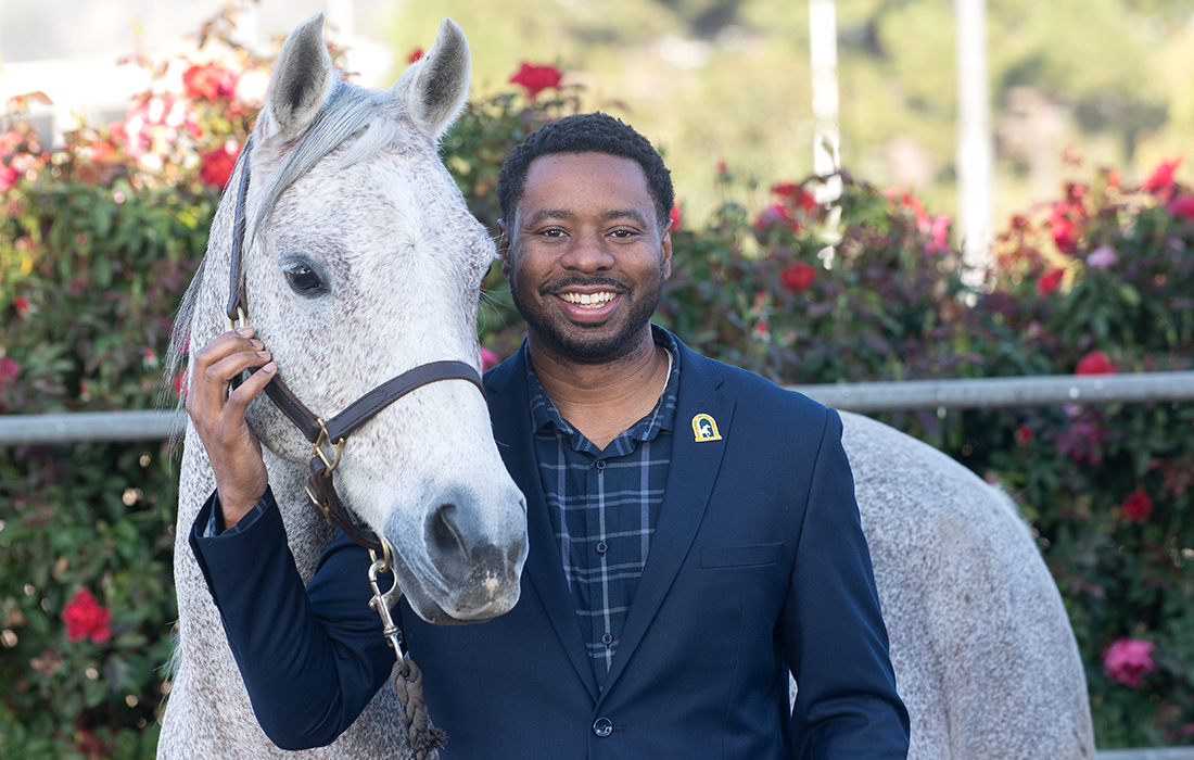 Anthony Stone poses with a white Arabian horse at the Kellogg Arabian Horse Center.