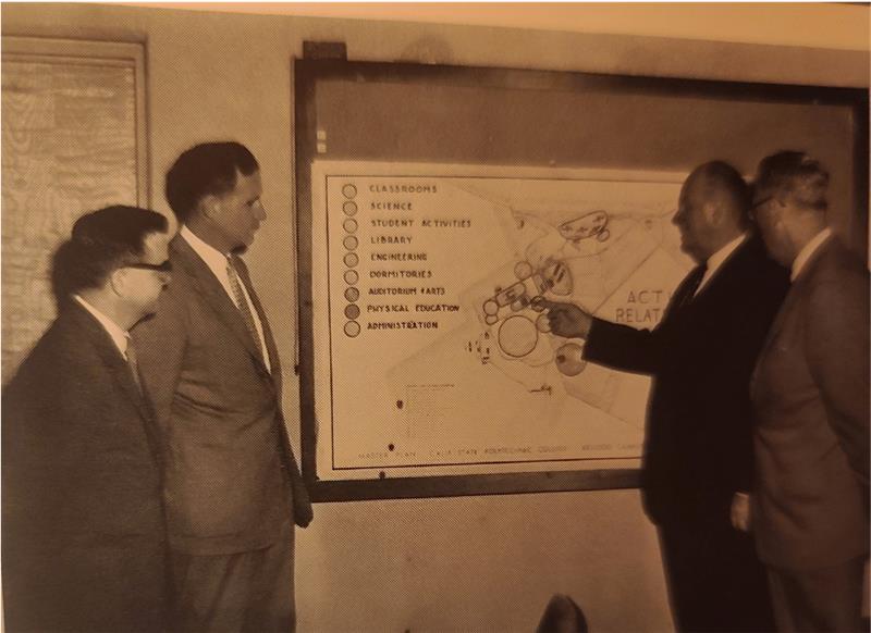 Group of men discuss plan for making the Health Center larger.