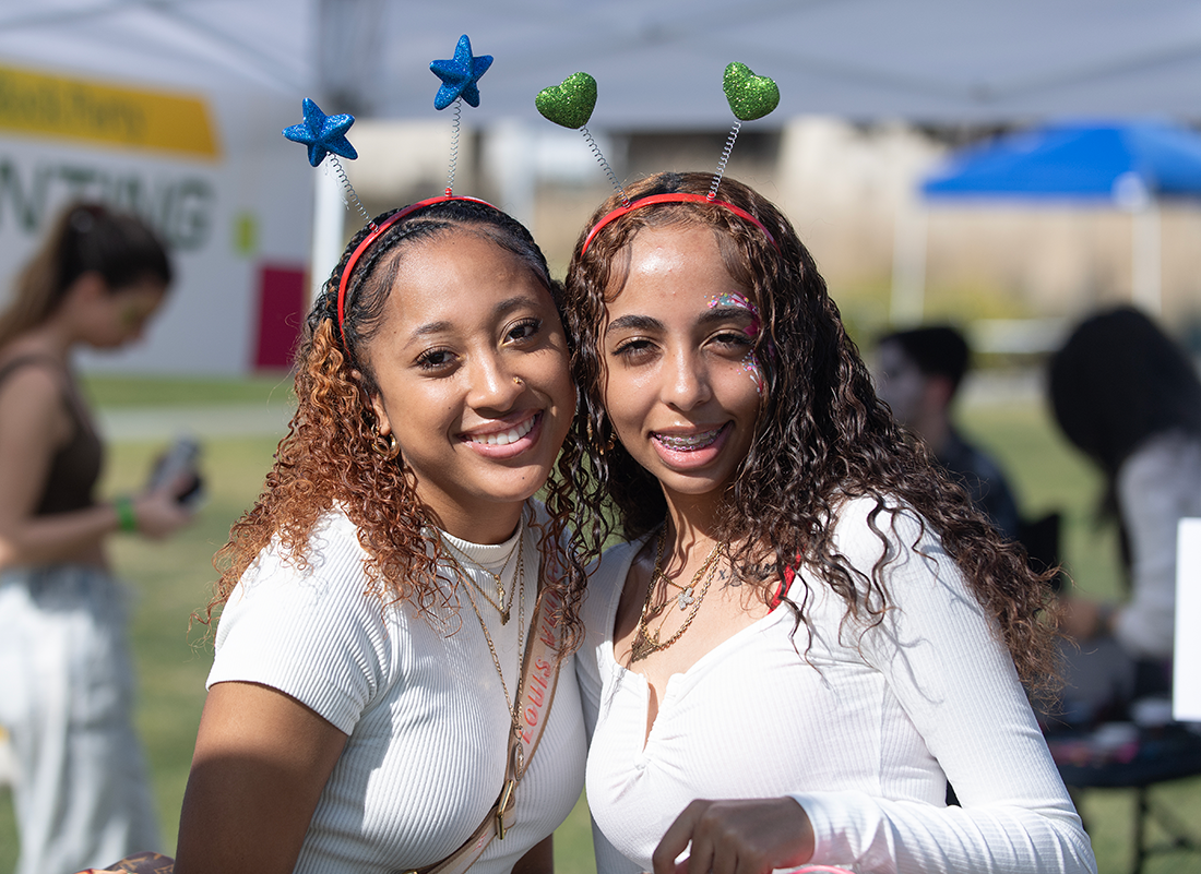 Two female students smile during the 2025 green and gold block party
