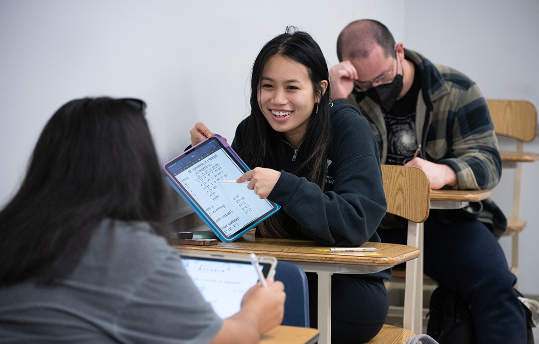 Female student smiles in math class while speaking to other students in class.
