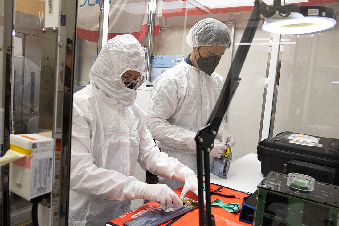 Two students in laboratory gear working together in the lab. 