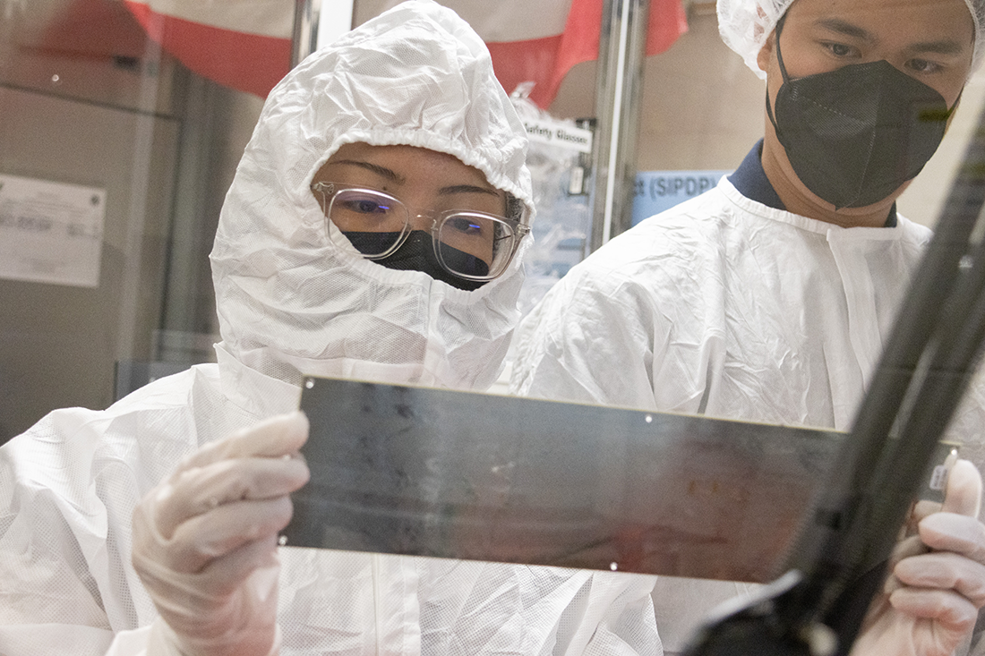 Two students hold up a piece of their work to inspect it. 