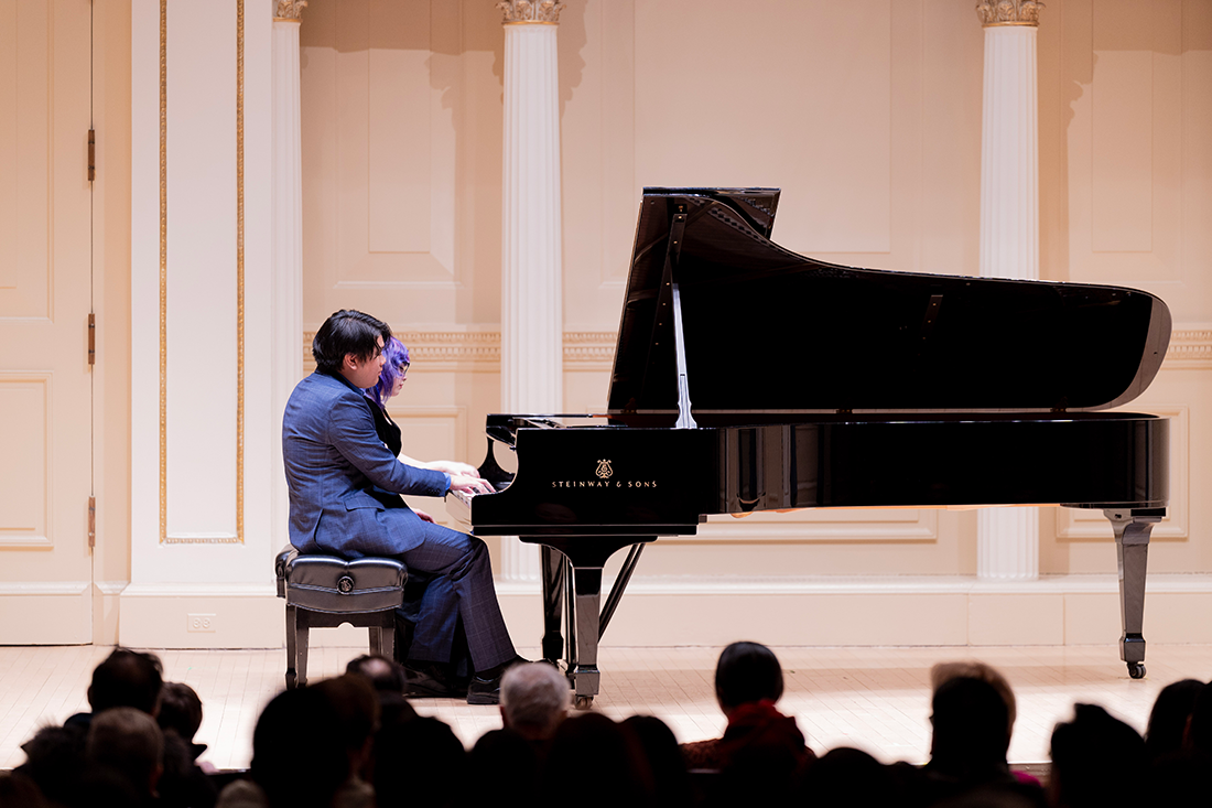 Evan Huang and Katie Bernardoni play a grand piano in Carnegie Hall.