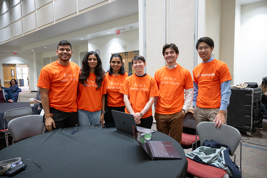 A group of students wearing AI for a better future Tshirts smile during the AI Hackathon.