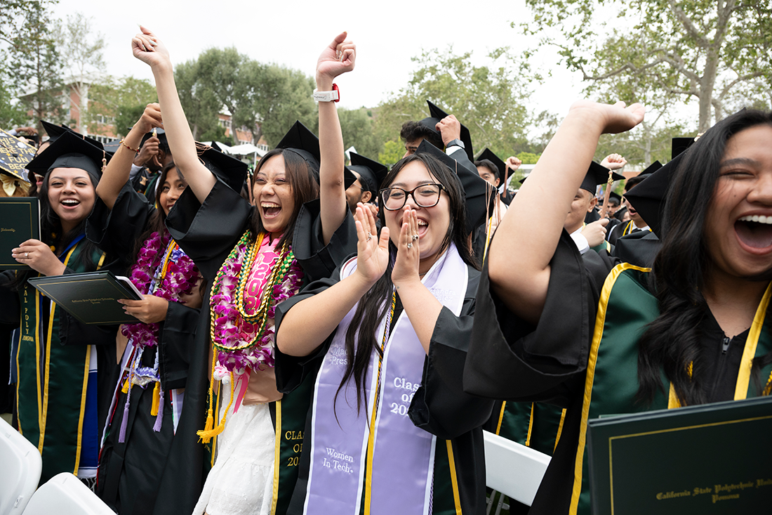 Female business students wearing Women in Tech stoles celebrate during commencement. 