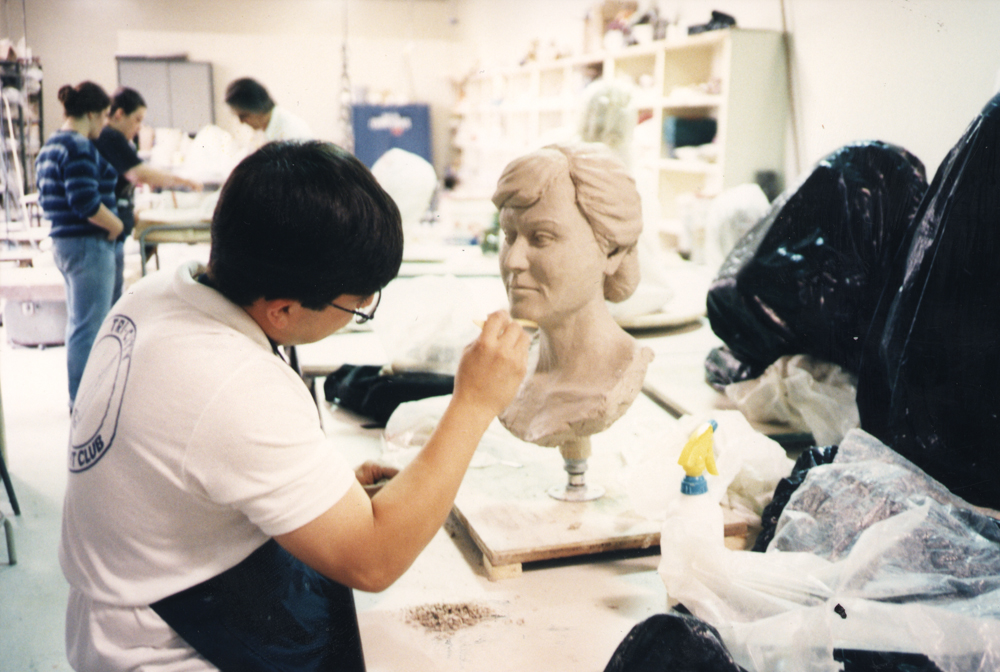 An art student works on sculpting a bust. 