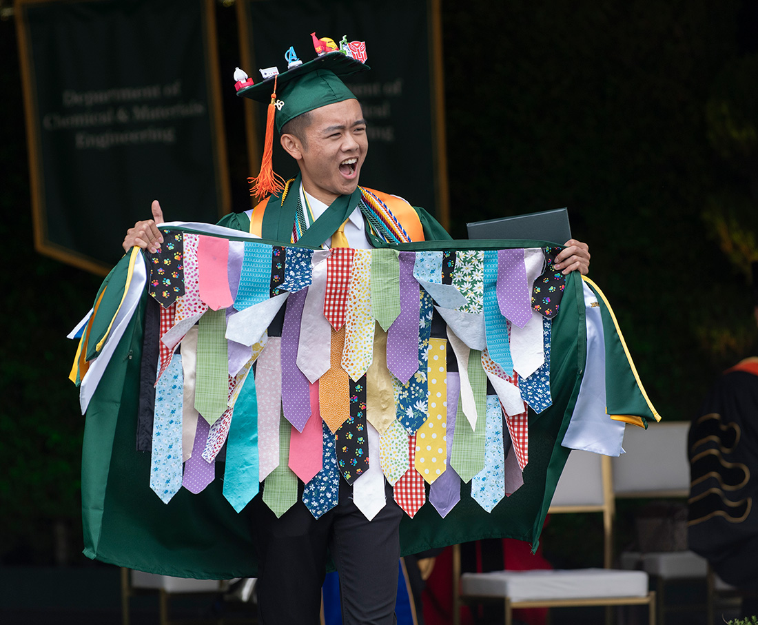 Male engineering grad holds open his graduation gown. 