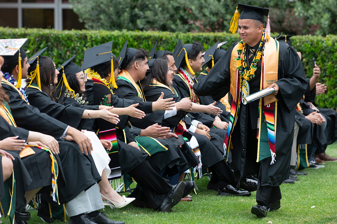 Male graduate high fives other students during the commencement ceremonies.